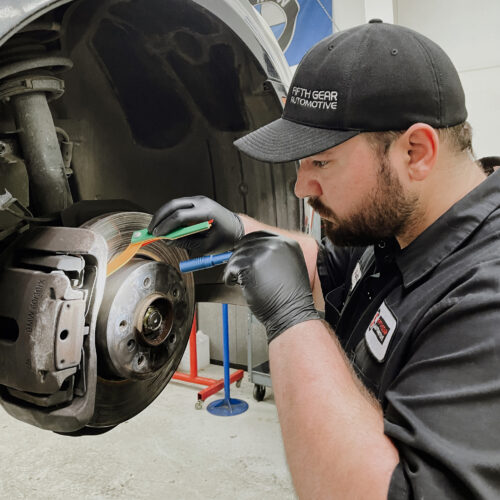A technician from Fifth Gear Automotive is inspecting a vehicle's brakes during its scheduled maintenance check.