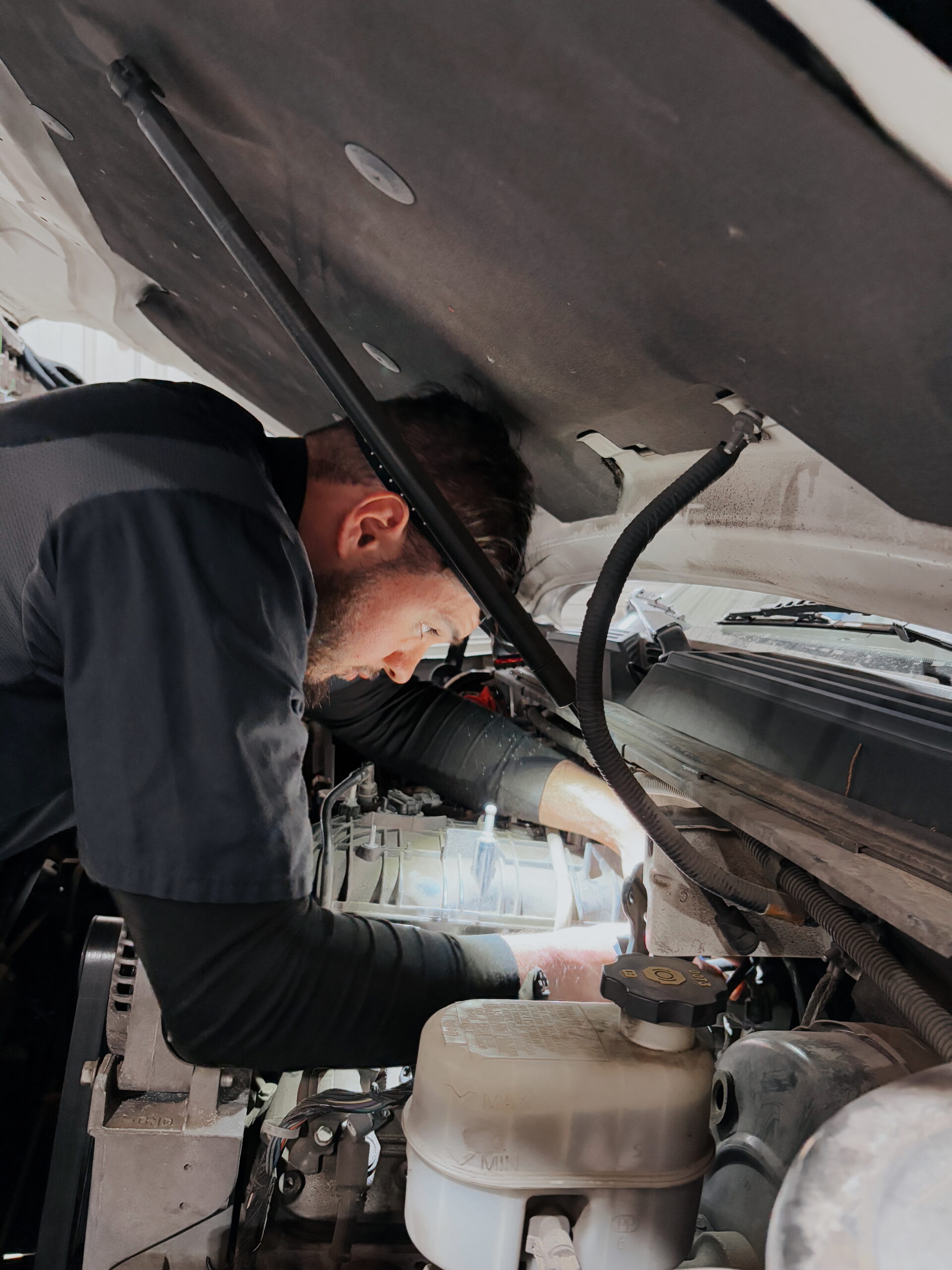 Auto Tech Performing a General Fluid Top Off on a Vehicle.